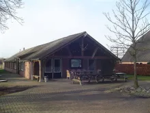 Kampgebouw met picknicktafels ervoor