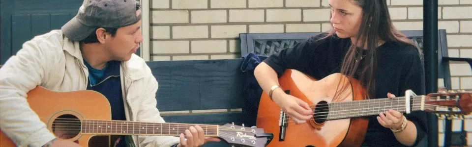 Twee tieners spelen samen gitaar tijdens het tienerkamp