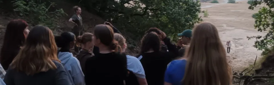 Tieners wandelen samen vanuit het bos naar de zandvlakte.