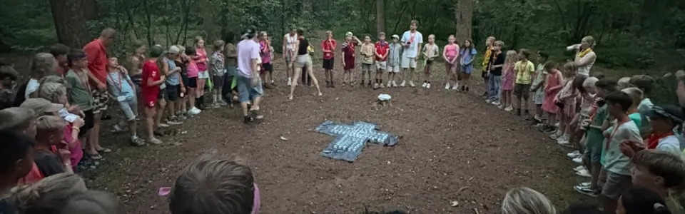Kinderen en leiding staan samen in een grote boskring