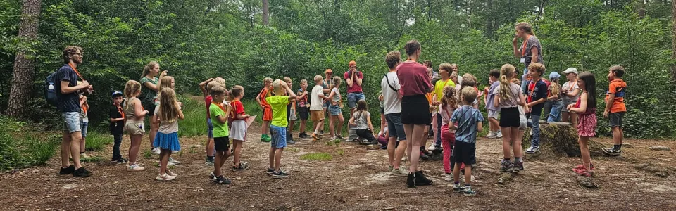 Kinderen en leiding verzamelen voor een bosspel tijdens het kamp