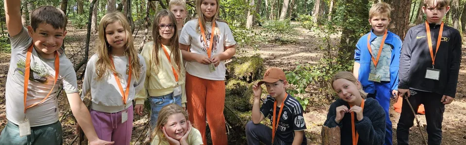 Kinderen poseren samen tijdens een vrolijke bosactiviteit op kamp.