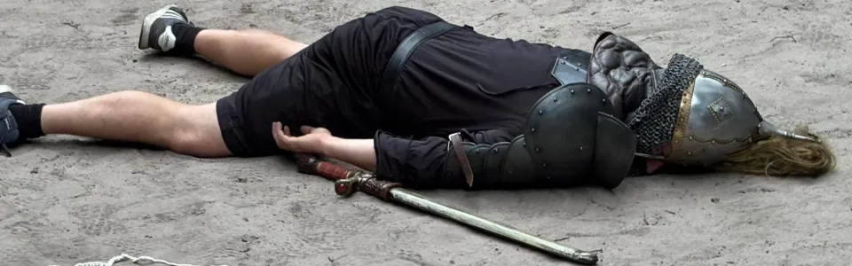 Verklede Viking ligt verslagen naast zijn zwaard in het zand