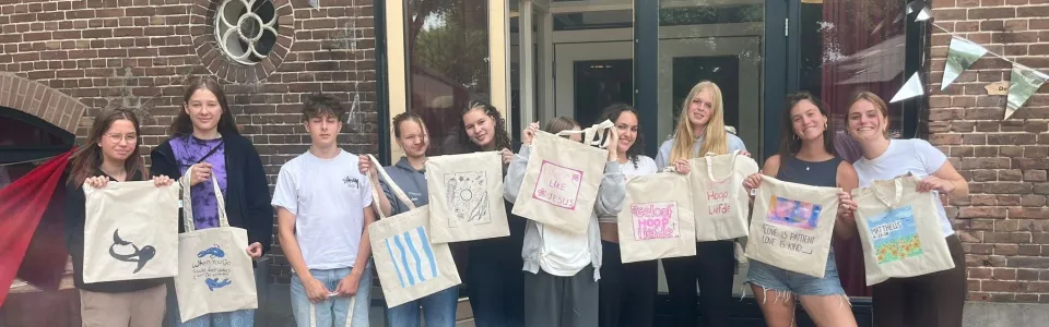Tieners tonen trots hun zelfversierde tassen tijdens het jeugdkamp