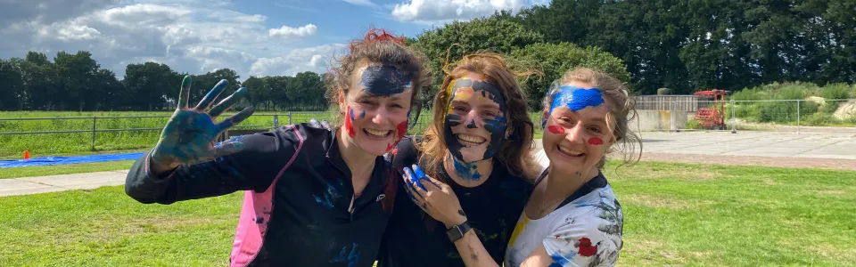 Deelnemers onder de verf lachen naar de camera
