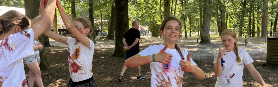 Meiden tonen trots hun beschilderde shirts tijdens het brugkamp.